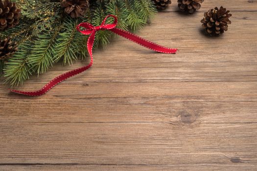 Christmas border design with pine cone, fir branches and ribbon over old oak wood