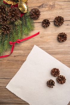 Christmas border design with pine cone, fir branches and ribbon on parchment paper over old oak wood