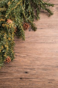 Christmas border design with pine cone and fir branches over old oak wood