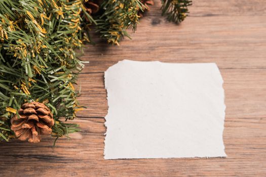 Christmas border design with pine cone and fir branches on parchment paper over old oak wood