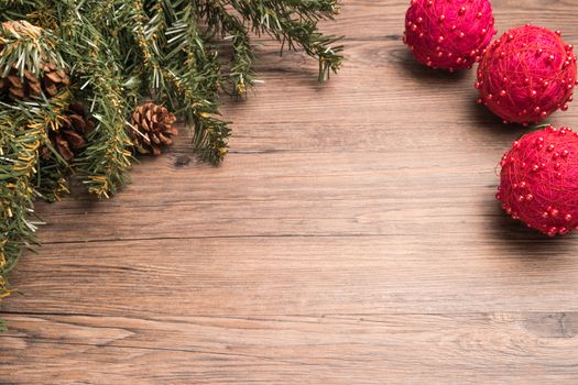 Christmas border design with pine cone, fir branches and christmas balls over old oak wood