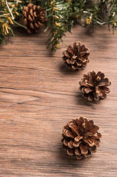 Christmas border design with pine cone and fir branches over old oak wood