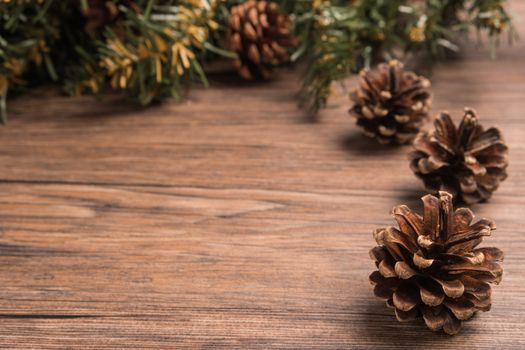 Christmas border design with pine cone and fir branches over old oak wood