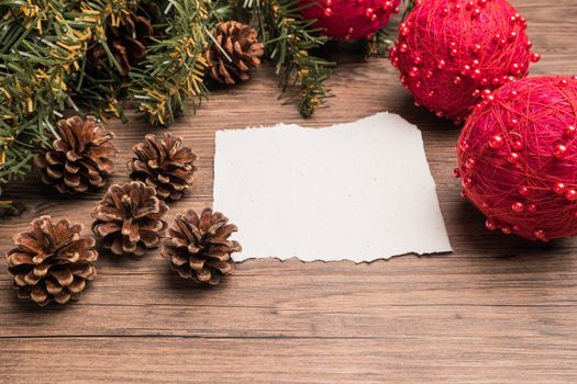 Christmas border design with pine cone, fir branches and christmas balls on parchment paper over old oak wood