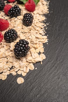 Healthy breakfast. Fresh granola, oatmeal with blackberries and raspberries on a black slate background. copy space