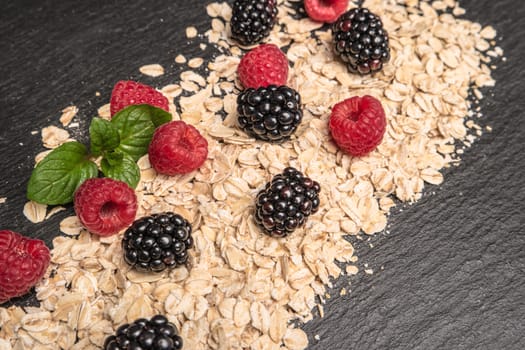 Healthy breakfast. Fresh granola, oatmeal with blackberries and raspberries on a black slate background. copy space