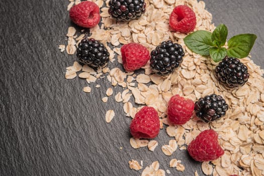 Healthy breakfast. Fresh granola, oatmeal with blackberries and raspberries on a black slate background. copy space