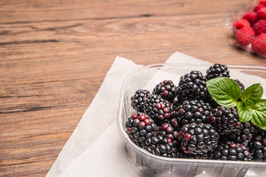 Ripe sweet blackberries and raspberries on wood table background