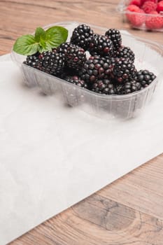 Ripe sweet blackberries and raspberries on wood table background