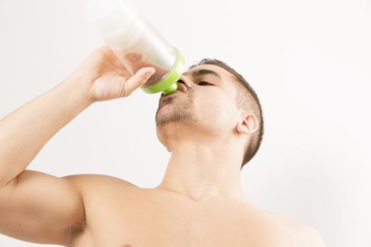 athletic young man with protein shake bottle. on white background
