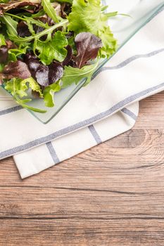 Fresh green salad with spinach, arugula, romaine and lettuce on plate. wood background