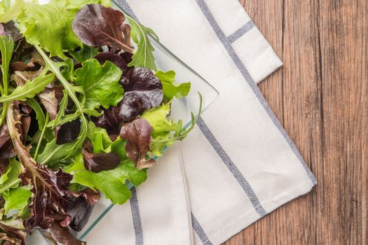 Fresh green salad with spinach, arugula, romaine and lettuce on plate. wood background