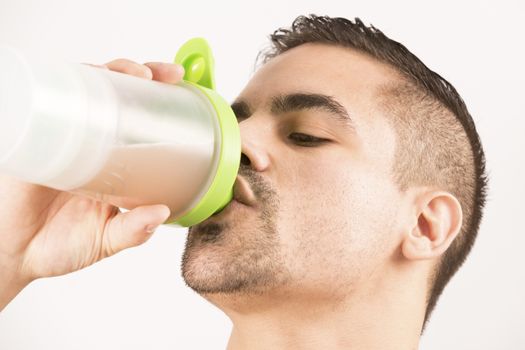 athletic young man with protein shake bottle. on white background