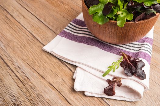 Fresh green salad with spinach, arugula, romaine and lettuce in a bowl on rustic wooden background