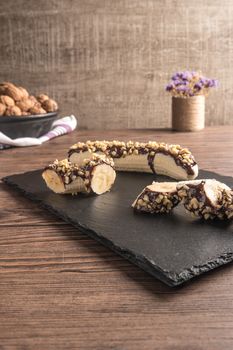 Fresh banana with melted chocolate and nuts coverage on slate