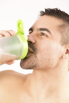 athletic young man with protein shake bottle. on white background