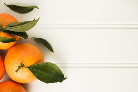 Fresh clementines on wooden board with leaves. Top view with copy space.