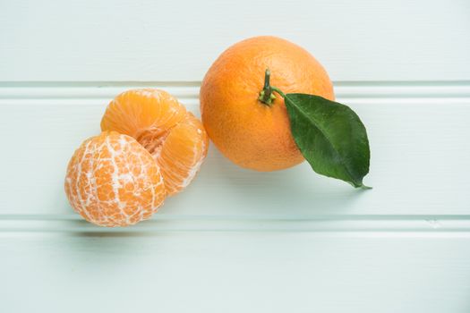 Fresh clementines on wooden board with leaves. Top view with copy space.