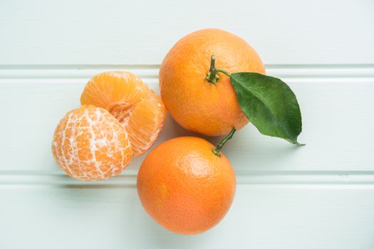 Fresh clementines on wooden board with leaves. Top view with copy space.