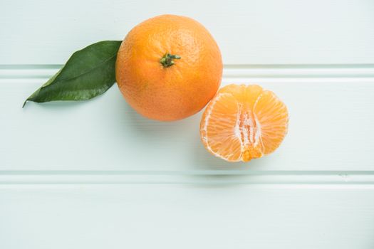 Fresh clementines on wooden board with leaves. Top view with copy space.