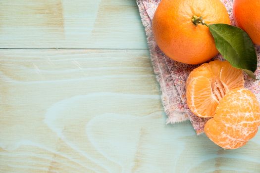 Fresh clementines on wooden board with leaves. Top view with copy space.