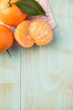 Fresh clementines on wooden board with leaves. Top view with copy space.