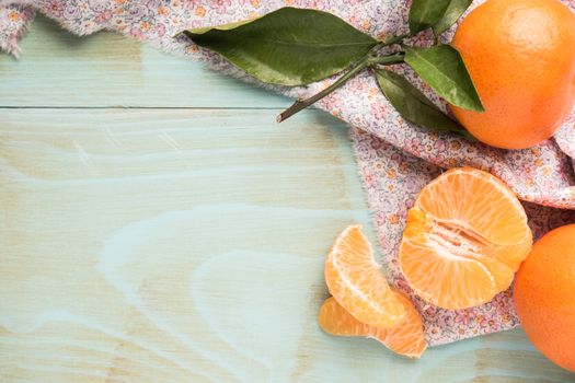 Fresh clementines on wooden board with leaves. Top view with copy space.