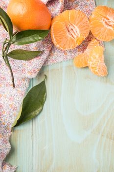 Fresh clementines on wooden board with leaves. Top view with copy space.