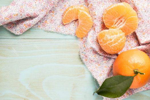 Fresh clementines on wooden board with leaves. Top view with copy space.