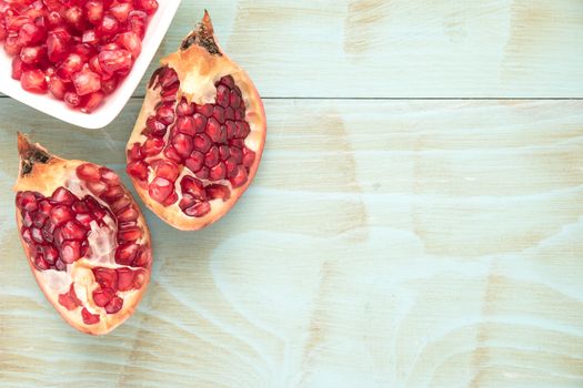 Red ripe peeled pomegranate on rustic wood board background. Top view, copy space