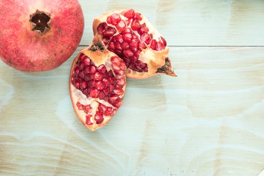 Red ripe peeled pomegranate on rustic wood board background. Top view, copy space