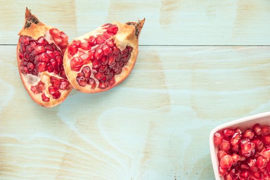 Red ripe peeled pomegranate on rustic wood board background. Top view, copy space