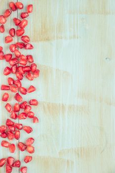 Red ripe peeled pomegranate on rustic wood board background. Top view, copy space