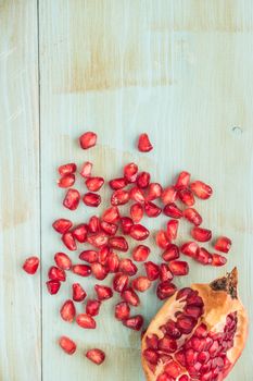 Red ripe peeled pomegranate on rustic wood board background. Top view, copy space