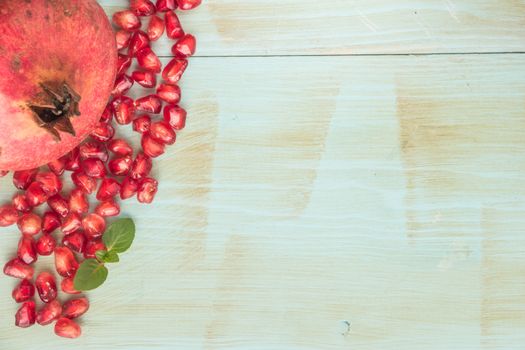 Red ripe peeled pomegranate on rustic wood board background. Top view, copy space