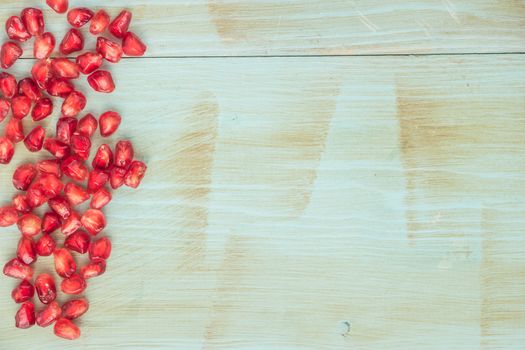 Red ripe peeled pomegranate on rustic wood board background. Top view, copy space