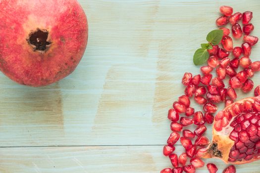 Red ripe peeled pomegranate on rustic wood board background. Top view, copy space