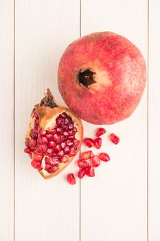 Red ripe peeled pomegranate on rustic wood board background. Top view, copy space