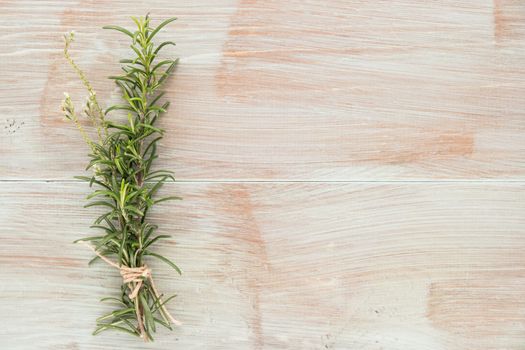 Bunch of fresh of garden rosemary on wooden table, rustic style, fresh organic herbs. Top view with copy space