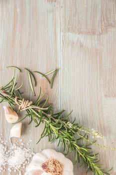 Bunch of fresh of garden rosemary on wooden table, rustic style, fresh organic herbs with salt and garlic. Top view with copy space