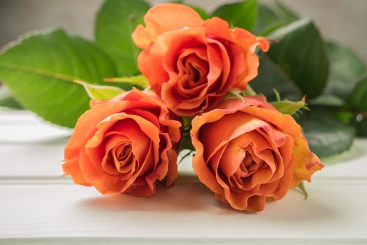 A bouquet of orange roses on wooden table. Copy space