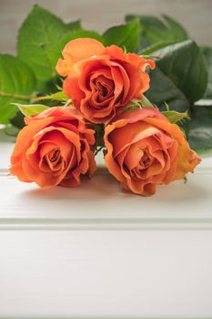 A bouquet of orange roses on wooden table. Copy space