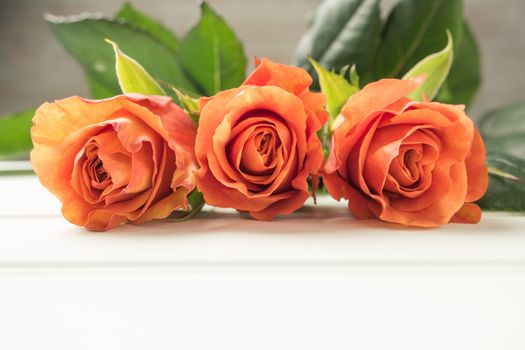 A bouquet of orange roses on wooden table. Copy space