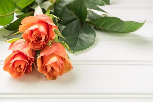 A bouquet of orange roses on wooden table. Copy space