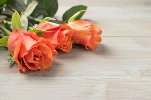 A bouquet of orange roses on wooden table. Copy space