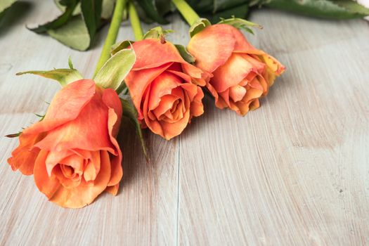 A bouquet of orange roses on wooden table. Copy space