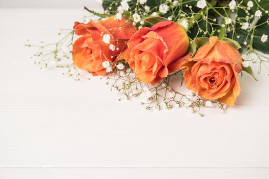 A bouquet of orange roses and gypsophila on wooden table. Copy space