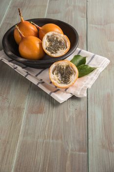 Fresh granadillas on wooden board with leaves.