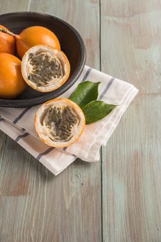 Fresh granadillas on wooden board with leaves.