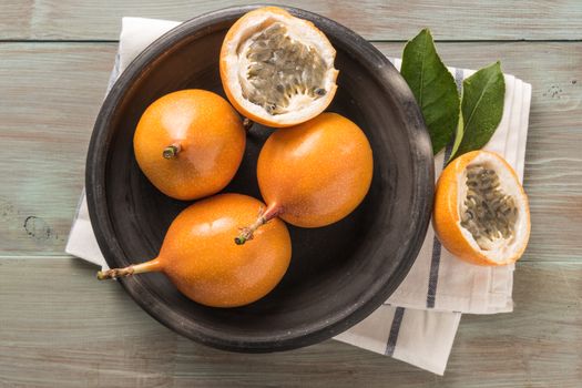 Fresh granadillas on wooden board with leaves.